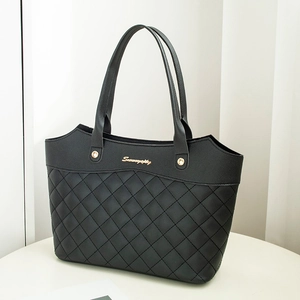 Sac fourre-tout noir matelassé avec logo doré et bord ondulé sur un socle blanc