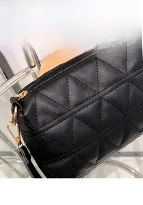 Gros plan du sac à bandoulière matelassé noir avec des détails métalliques dorés fins