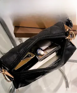 Détail du sac bandoulière noir matelassé montrant l'intérieur spacieux et les accessoires