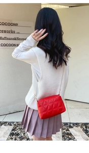 Détail du sac bandoulière matelassé rouge avec chaîne dorée élégante et texture géométrique