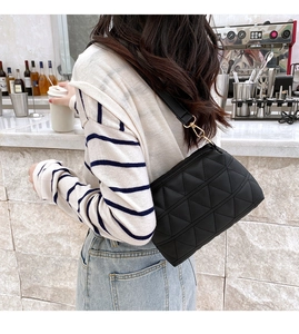 Vue lifestyle d'un sac bandoulière noir matelassé avec des détails métalliques dorés