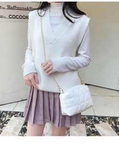 Sac bandoulière matelassé blanc avec chaîne dorée porté par un mannequin