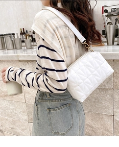 Gros plan sur un sac bandoulière blanc matelassé avec des détails dorés