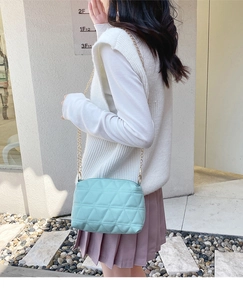 Détail du sac bandoulière matelassé vert menthe avec motifs triangles et chaîne dorée