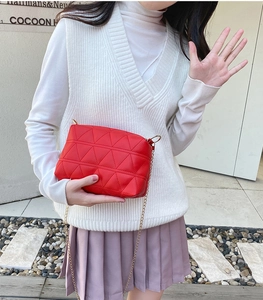 Femme portant un sac bandoulière rouge matelassé avec une chaîne dorée en extérieur