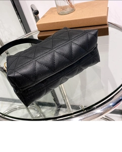 Détail du sac en cuir matelassé noir avec coutures triangulaires sur une table en verre