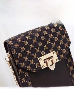 Close-up of golden hardware lock and clover pattern on brown faux leather crossbody bag