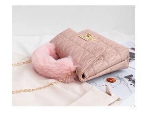 Close-up of quilted leather handbag with pink faux fur handle and golden metal twist lock