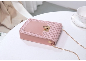 Detailed view of pink floral print crossbody bag with gold metal lock and chain strap