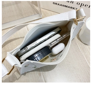 Internal view of white underarm bag with floral embroidery showing spacious capacity