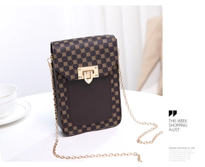 Detail of vintage patterned crossbody phone bag with gold shield lock and chain strap
