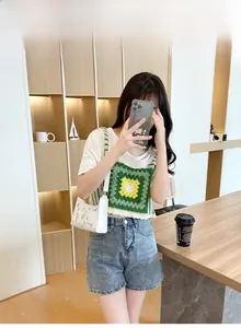 Detailed view of embroidered underarm bag paired with a crochet vest and denim shorts