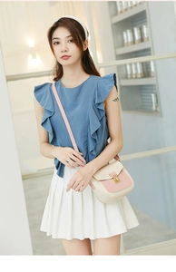 Detail of pink and white croc-textured leather crossbody bag on female model outfit