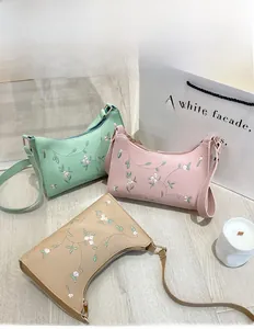 Detail of floral embroidery on pastel PU leather shoulder bags in mint, pink and khaki