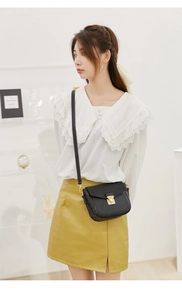 Close-up of black crocodile pattern crossbody bag with a square gold metal buckle