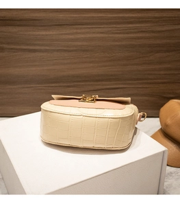 Close-up of crocodile pattern leather small crossbody bag with gold twist lock and flap