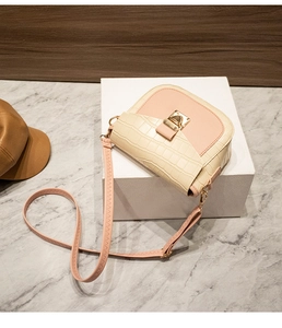 Close-up of pink and cream crossbody bag with crocodile texture and gold metal lock