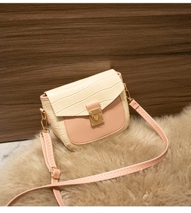 Detail of faux crocodile texture and gold heart clasp on pink and beige crossbody bag