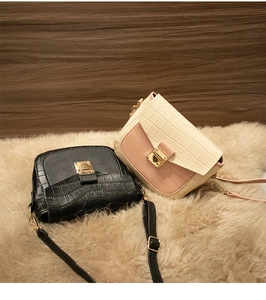 Detail of square crossbody bags with crocodile pattern and golden metal buckles on fur rug