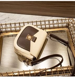 Detail of two-tone crossbody bag featuring cream crocodile texture and brown leather
