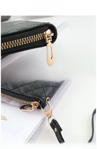 Detail of green quilted leather wallet with gold zipper and detachable hand strap