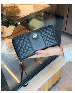 Detail of black quilted leather trifold wallet with gold metal buckle and hand strap