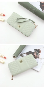 Detailed view of light green quilted trifold wallet with gold buckle and wrist strap