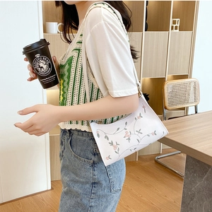 Minimalist white shoulder bag with floral embroidery and elegant half-moon shape