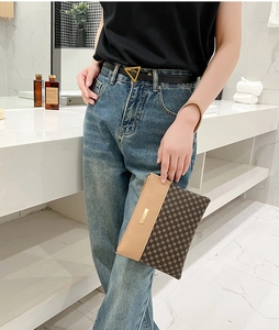 Detail of printed geometric clutch with gold metal plate and brown wristlet strap