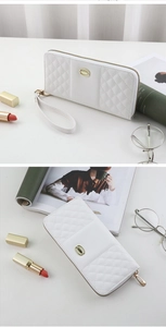 Close-up of a white quilted long wallet with golden buckle and detachable wrist strap