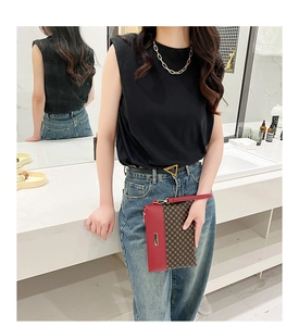 Close-up of stylish red and monogram pattern clutch bag with wrist strap on marble