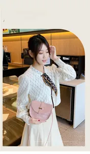 Close-up of light pink crocodile pattern saddle bag with a golden metal buckle lock