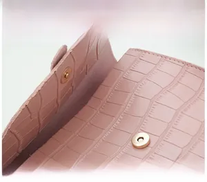 Close-up of pink saddle bag featuring crocodile texture and a gold magnetic clasp