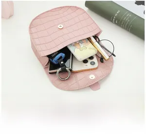 Open pink saddle bag showing interior space with phone, keys, and cosmetics