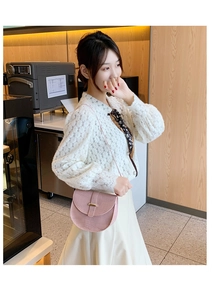 Pink crocodile pattern saddle bag with gold buckle worn by a model in a cozy cafe