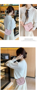 Detailed macro view of pink crocodile texture on a mini saddle bag with gold metal buckle
