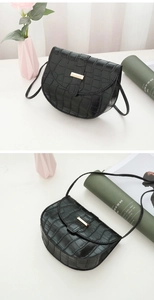 Detail of black faux crocodile saddle bag featuring a sleek gold metal buckle and strap
