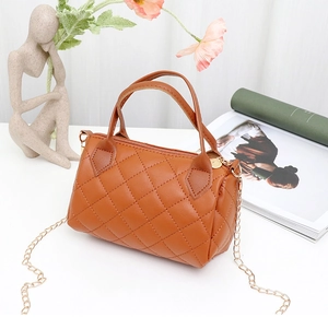 Detail of brown quilted barrel bag featuring twin handles and a gold chain strap