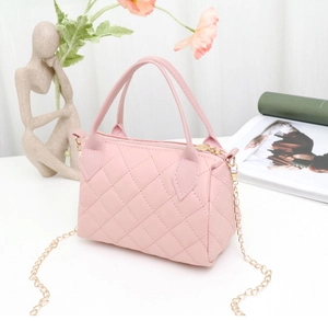 Detailed macro view of pink quilted texture on the bag with golden chain hardware