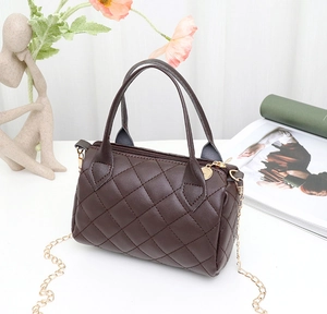 Detailed close-up of dark brown quilted cylinder bag with gold chain and handle
