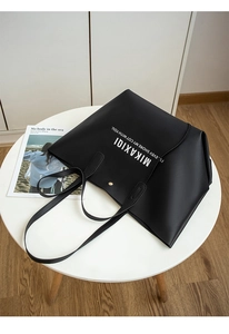Detail of black matte leather tote bag featuring white artistic lettering and magnetic closure