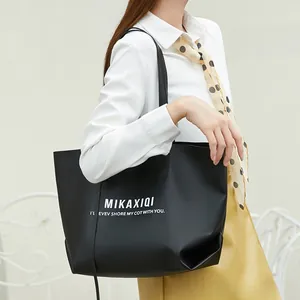 Fashionable black large capacity tote bag styled with a white shirt and yellow skirt