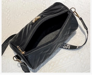 Macro view of black quilted cylinder bag showing gold bow detail and wide fashion strap