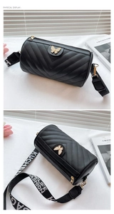 Detail view of black cylinder crossbody bag with V-quilted pattern and golden butterfly buckle