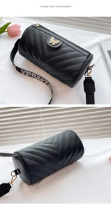 Detail of black V-quilted cylinder bag with golden butterfly lock and fashion strap