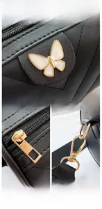 Detail of black pebbled leather cylinder bag with butterfly decor and gold hardware
