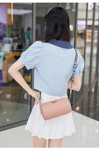 Close-up of pink V-quilted cylinder bag with decorative bow and branded wide strap