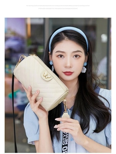 Detail of cream quilted cylinder bag with butterfly buckle and GO CITY NEW wide strap