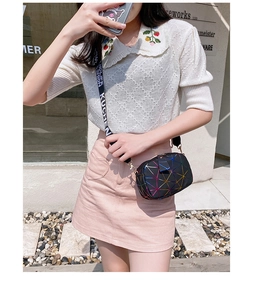 Street style shot of a black geometric crossbody bag with a wide printed strap on a model
