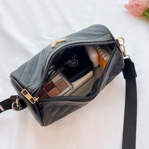 Black cylinder crossbody bag with quilted V-pattern and white butterfly buckle detail